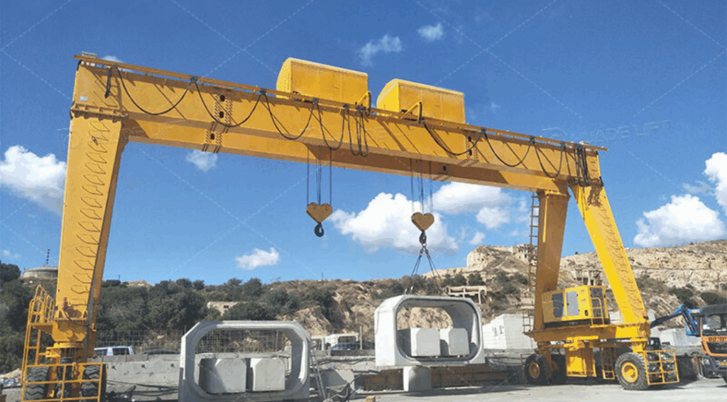 A rubber tyred gantry crane lifting a precast concrete beam during heavy construction work.